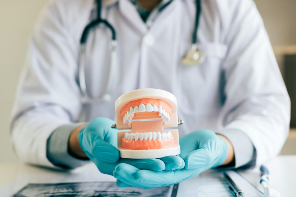 dentist-holding-dentures-in-office-room--1024x682